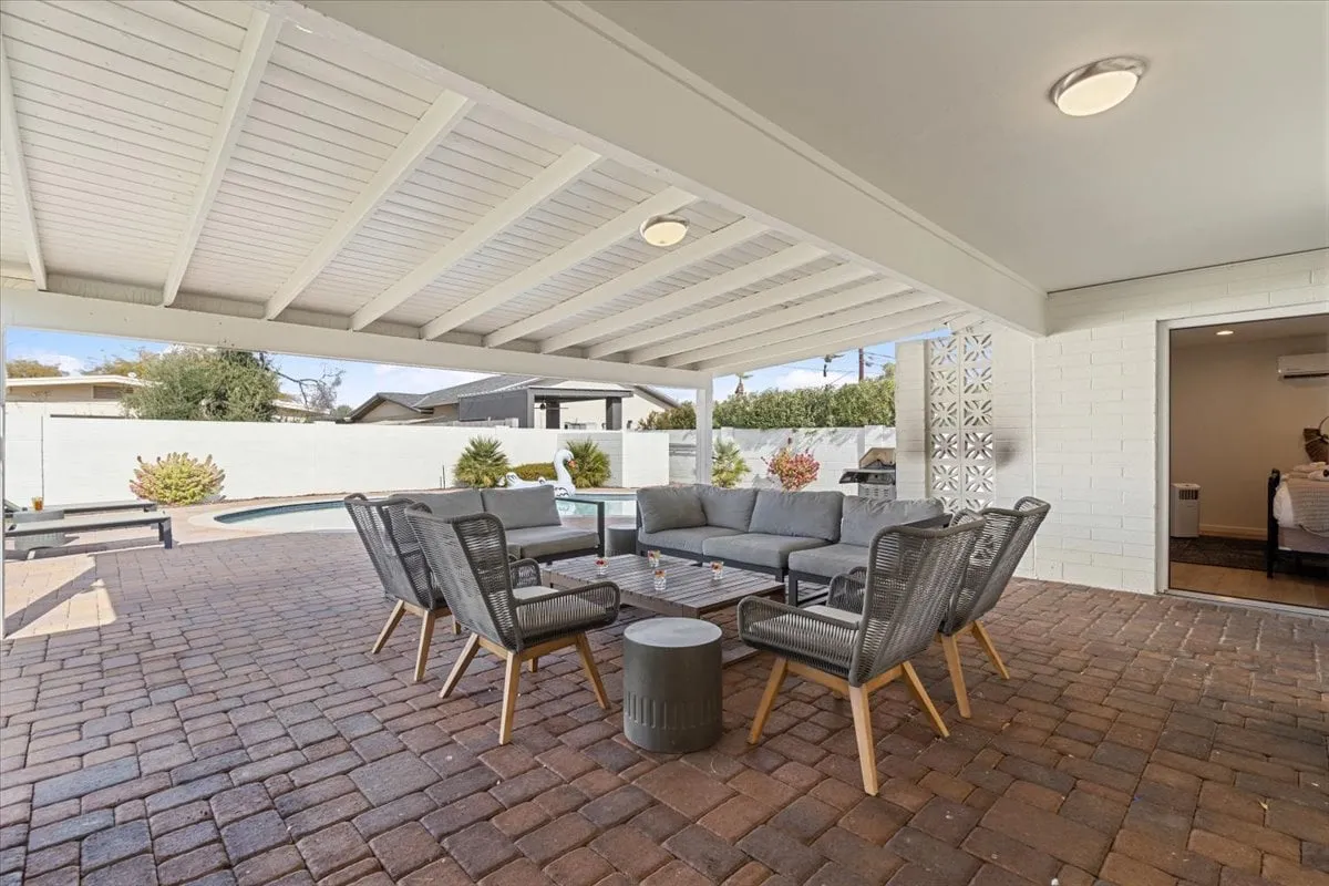 An inviting backyard scene featuring a sitting area adjacent to a sparkling swimming pool, with warm outdoor lighting that suggests a welcoming atmosphere for both day and evening events. The setting is private, perfect for relaxing or hosting casual gatherings with colleagues or friends.