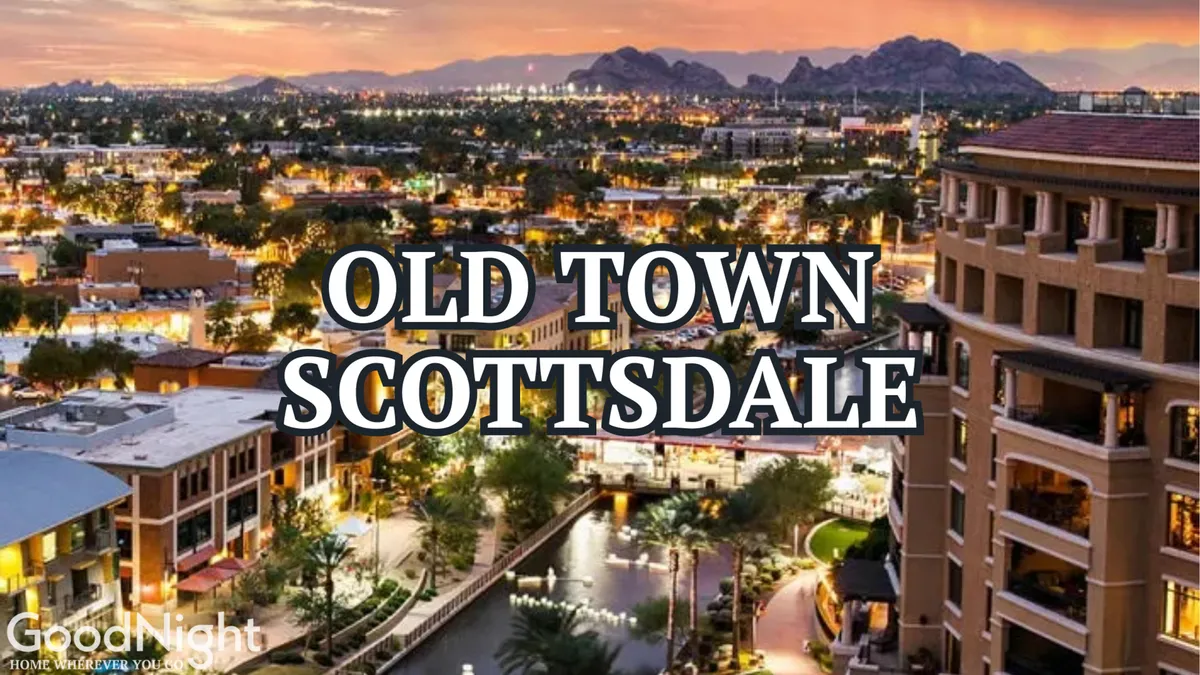 A vibrant view of Old Town Scottsdale, featuring prominent signage by a scenic waterway, surrounded by bustling buildings with mountains visible in the distance. The image captures people strolling, dining outdoors, and shopping, giving a sense of the area's energetic and social atmosphere.