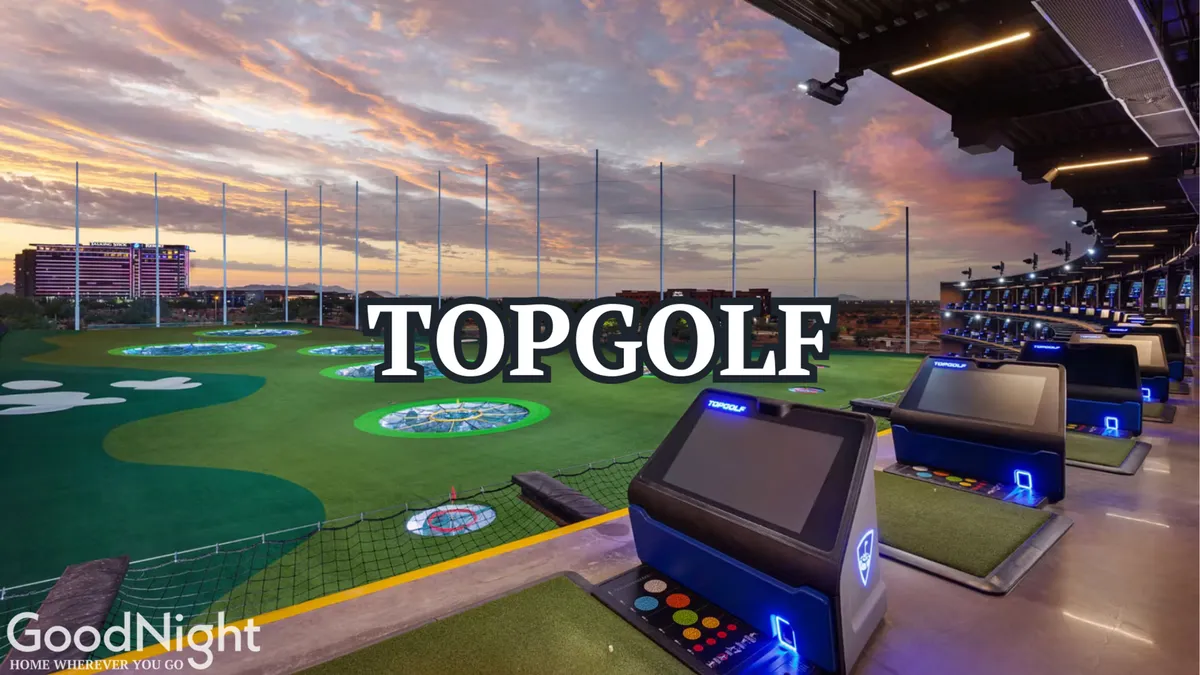 Modern driving range bays overlook a manicured green, with LED screens and vibrant landscaping. The scene is lively, suggesting socializing, practice, and entertainment—all with a city skyline visible in the distance.